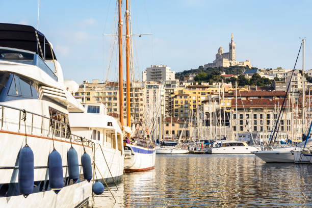 luxus-yachten und segelboote vor anker im alten hafen von marseille, frankreich, mit basilika notre-dame de la garde auf dem hügel bei sonnenuntergang. - marseille notre dame de la garde tower cathedral stock-fotos und bilder