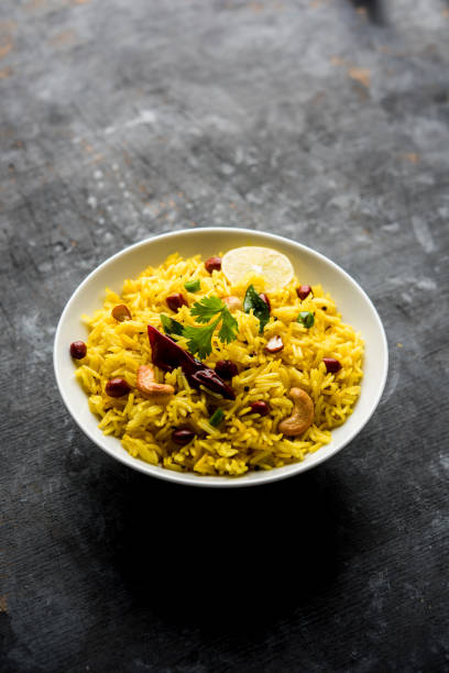 lemon rice to południowoindyjski ryż kurkumy lub maharashtrian przepis o nazwie fodnicha bhat wykonane przy użyciu resztek ryżu przyozdobiony orzechami liści curry i soku z cytryny, selektywne skupienie - healthy eating close up lemon nut zdjęcia i obrazy z banku zdjęć