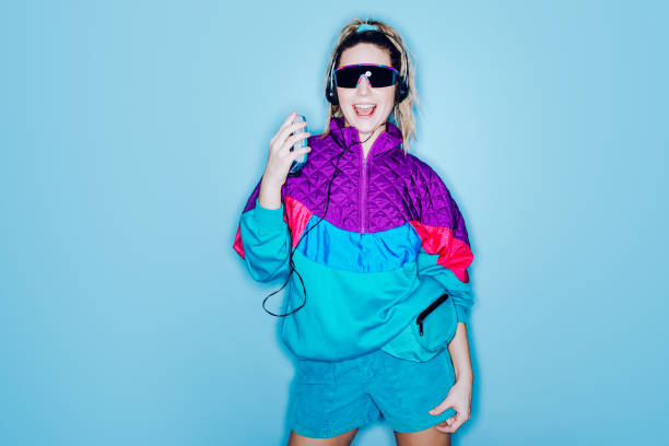 Retro Fashion Style Woman Eighties Era A woman wearing clothing styled after the 1980's and 1990's listens to music on her personal cassette tape player in front of a large bright blue background.  Shot with a ring flash. bizarre fashion stock pictures, royalty-free photos & images