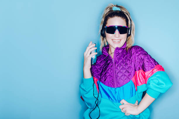 Retro Fashion Style Woman Eighties Era A woman wearing clothing styled after the 1980's and 1990's listens to music on her personal cassette tape player in front of a large bright blue background.  Shot with a ring flash. 1990s style stock pictures, royalty-free photos & images