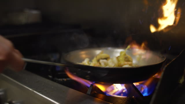 Slow Motion Shrimp and Mushroom Flambe in Pan of Oil in Commercial Kitchen