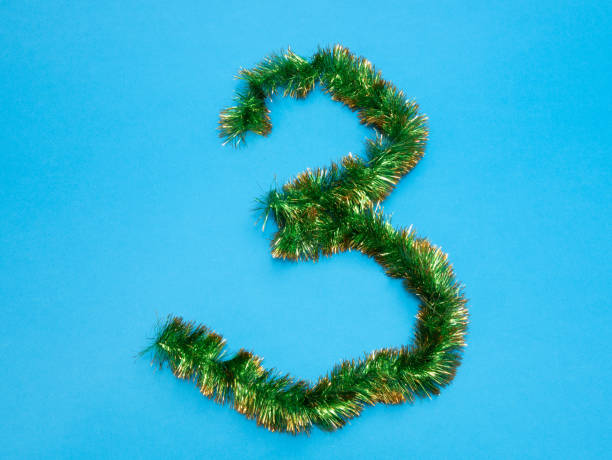 istock number three 3 made of green tinsel on blue background 1084196164