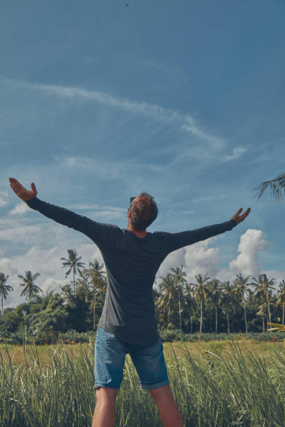 istock Man enjoying tropical climate with arms wide open. 1084201742