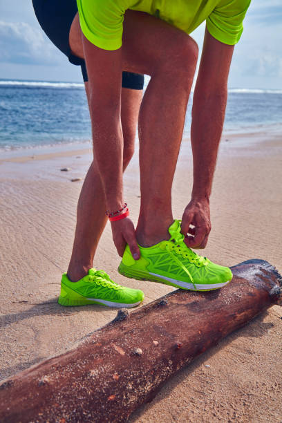 istock Man tying running sneakers on a tropical exotic beach. 1084205374