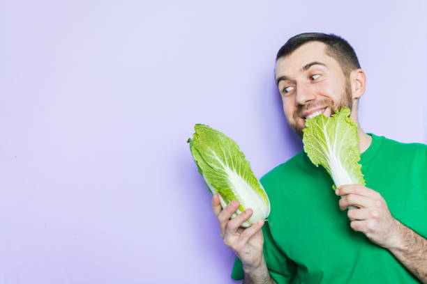 istock Young man biting on a leaf of Beijing napa cabbage 1084207966
