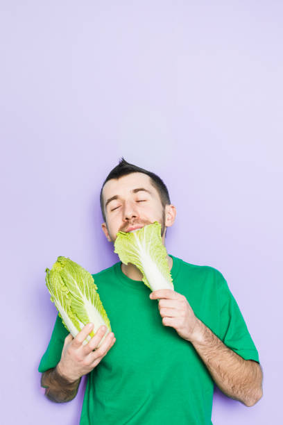 istock Young man biting on a leaf of Beijing napa cabbage 1084208636