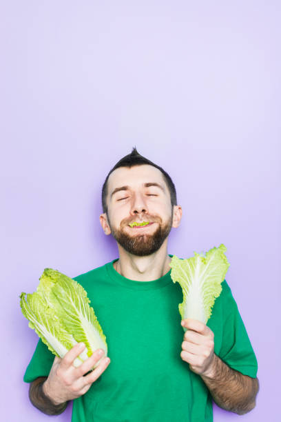 istock Young man biting on a leaf of Beijing napa cabbage 1084210366