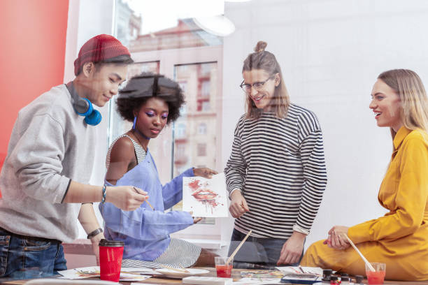 istock Four creative students of art school feeling joyful while painting 1084218074
