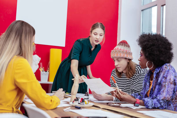 istock Blonde-haired stylish teacher of art explaining material to students 1084218290