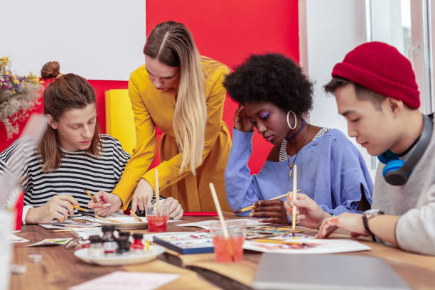 istock Helpful teacher assisting her art students in the process of work 1084218424