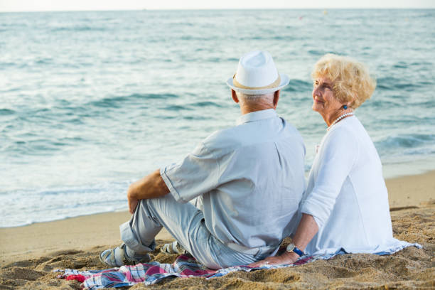istock female and male in hat sitting on the beach 1084220954