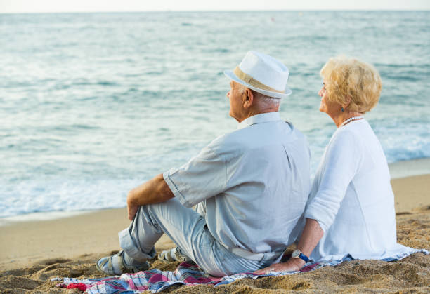 istock Mature man and woman sitting back on towel 1084220962