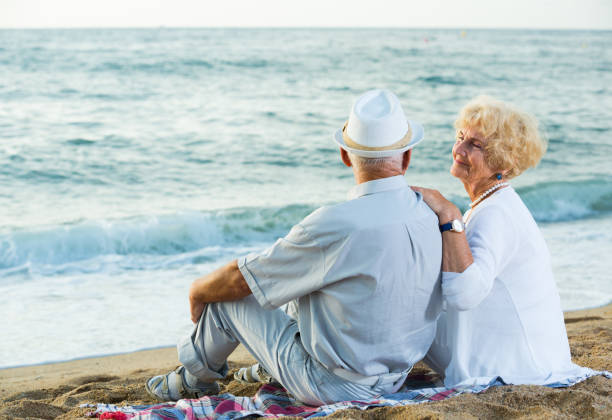 istock Mature man and woman sitting back on towel 1084220966
