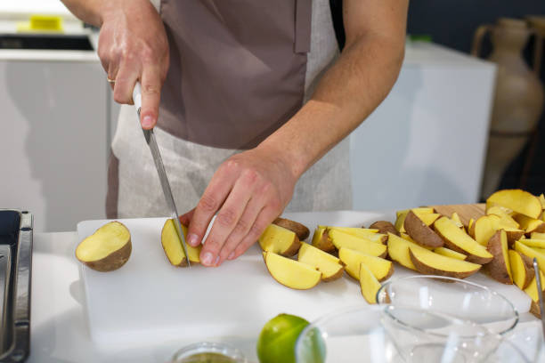 istock Chef cutting potatoes wedges on white table 1084221126