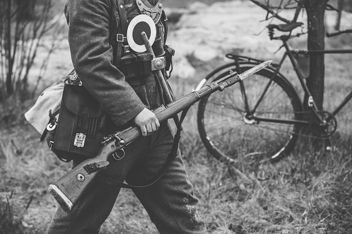 Re-enactor Dressed As World War II German Soldier Feldgendarm Holding Rifle. Photo In Black And White Colors. Soldier Holding Weapon. German Military Ammunition Of A German WW2 Soldier.