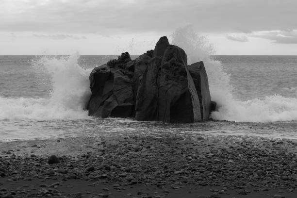 Waves breaking at the rock on the coast. Praia Formosa beach in Funchal, Portugal
