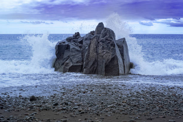 Waves splashing at the rock at sunset. Praia Formosa beach in Funchal, Portugal