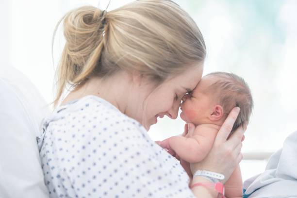 Touching Foreheads A mother is touching foreheads with her newborn daughter. They are laying in a hospital bed. childbirth photos stock pictures, royalty-free photos & images
