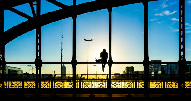 istock Silhouette Man Sitting On Bridge Against Sky During Sunset 1084263732