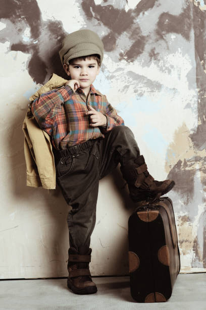 Boy wearing vintage puts his leg on suitcase, retro stylized shot, 50s-60s