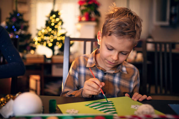 Little boy painting Christmas card