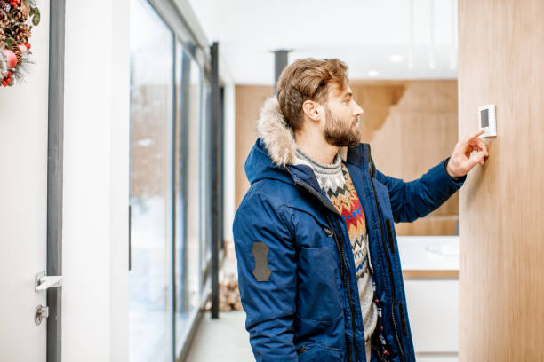 istock Man adjusting temperature with thermostat at home 1084278286