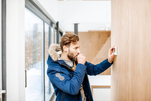 istock Man adjusting temperature with thermostat at home 1084278346