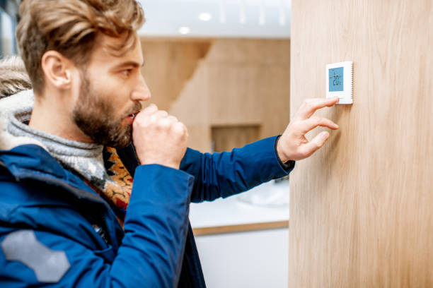 istock Man adjusting temperature with thermostat at home 1084278348
