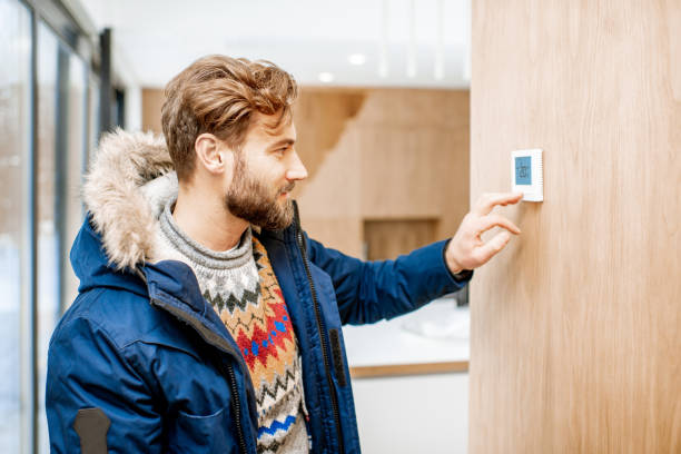 istock Man adjusting temperature with thermostat at home 1084278392