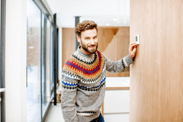 istock Man adjusting temperature with thermostat at home 1084278502