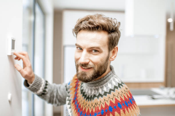 istock Man adjusting temperature with thermostat at home 1084278574