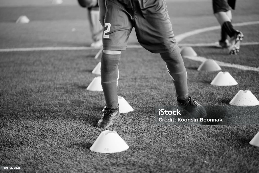 black and white picture of soccer player Jogging and jump between cone markers on artificial turf for soccer training black and white picture of soccer player Jogging and jump between cone markers on artificial turf for soccer training. Football or Soccer Academy. Soccer Stock Photo