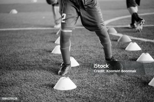 Black And White Picture Of Soccer Player Jogging And Jump Between Cone Markers On Artificial Turf For Soccer Training Stock Photo - Download Image Now