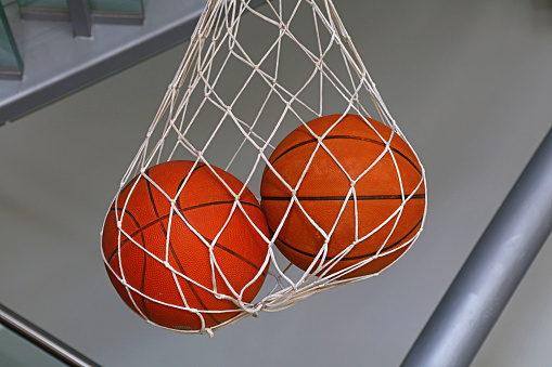 Close up two basketball balls hanging in mesh sack, low angle side view