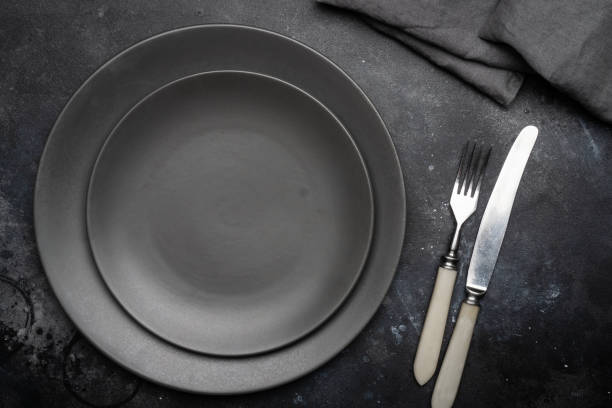 istock Empty gray plate (ceramic) on a dark gray background with a knife and fork, decorated with a bouquet of lavender and a napkin. Gray minimalistic concept. Copy space. 1084280710