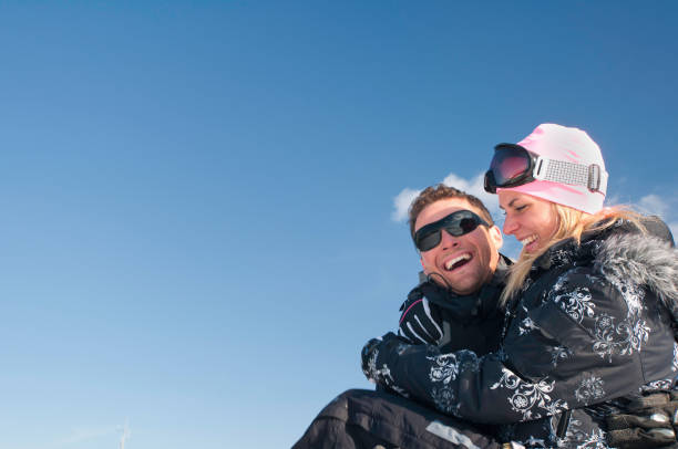 istock Smiling Man Carrying Woman While Standing Against Blue Sky During Winter 1084282272