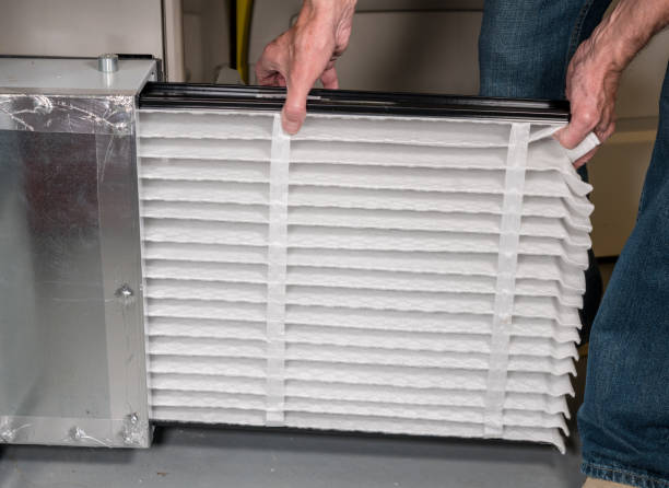 Senior man inserting a new air filter in a HVAC Furnace Senior caucasian man changing a folded air filter in the HVAC furnace system in basement of home filtration stock pictures, royalty-free photos & images