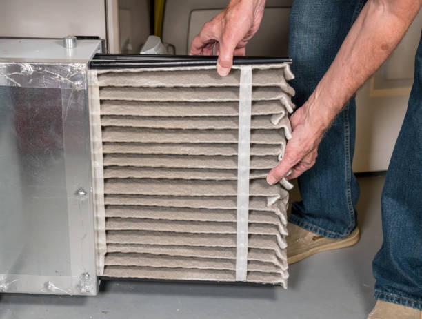 Senior man changing a dirty air filter in a HVAC Furnace Senior caucasian man changing a folded dirty air filter in the HVAC furnace system in basement of home filtration stock pictures, royalty-free photos & images