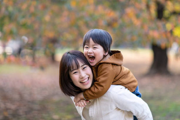 Young mother and son playing together in public park stock photo