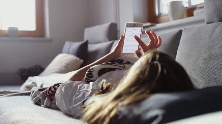 MS Teenage girl relaxing on sofa with smart phone