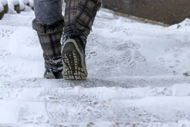 A woman goes down a staircase in winter. In winter there is a danger of slipping on a snow-covered staircase.