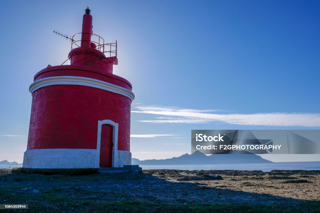 Red lighthouse in front of island Red lighthouse on the Galician coast off the island in Galicia, Pontevedra, Spain Atlantic Ocean Stock Photo
