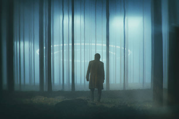 istock Man in the forest at night with landing UFO 1084312528