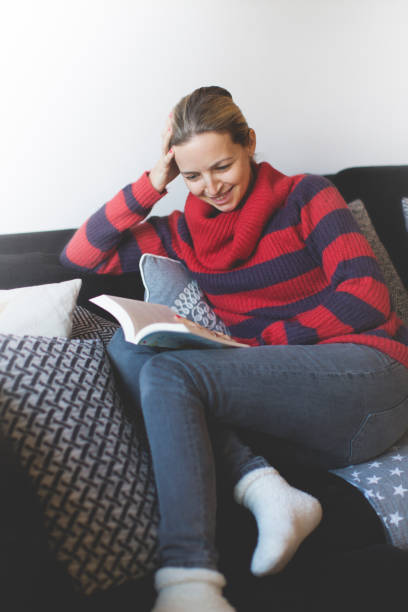 istock Woman With Book Sitting On Sofa At Home 1084312870