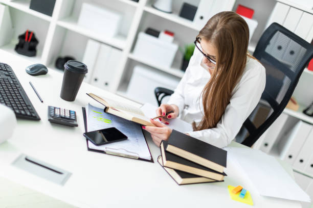 istock A young girl working in the office with books and documents. 1084331956