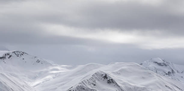 istock Sunlight snowy mountains in fog and gray overcast sky 1084332212