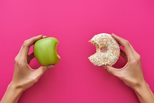 Concepto de dieta o buena salud. Joven, tratando de elegir entre apple y donut photo