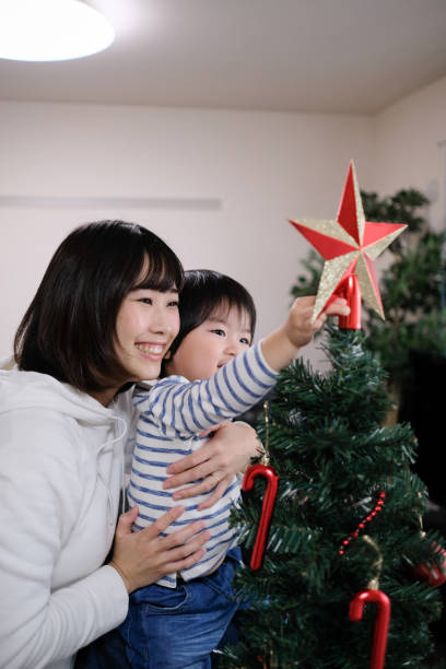 istock Mother and child putting star on Christmas tree 1084347618