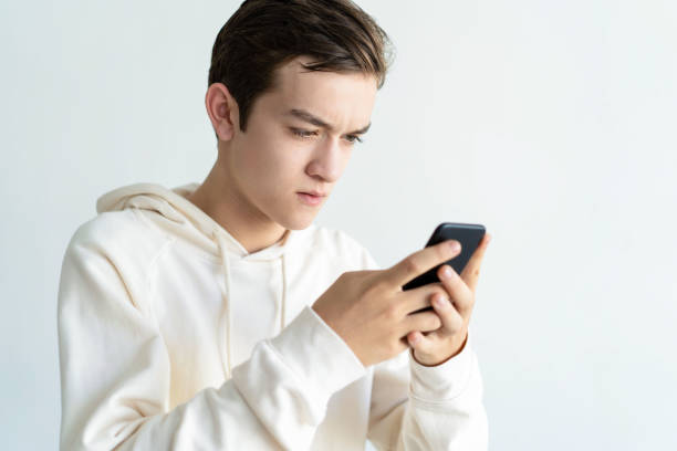 istock Focused teen boy holding and using smartphone 1084353492