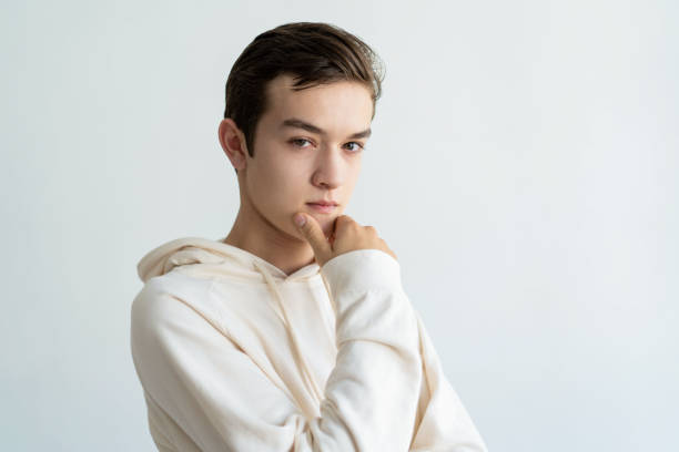 istock Thoughtful teen boy touching chin and looking at camera 1084353600
